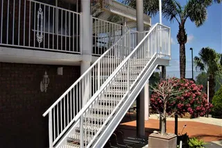 White metal exterior staircase and balustrade beside a brick home