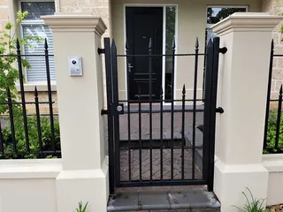 Black pedestrian gate between rendered pillars