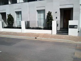 Black metal front fence and gate outside a white home