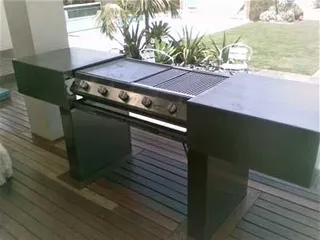Built-in barbecue with black metal bench cabinets on a timber deck