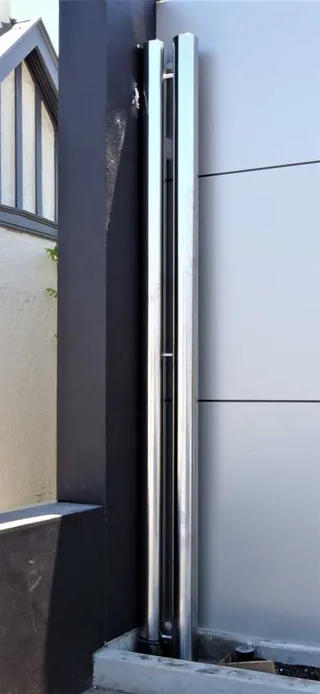 Tall polished stainless steel architectural posts beside a wall