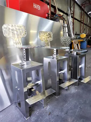 Three fabricated stainless steel seat bases in the workshop