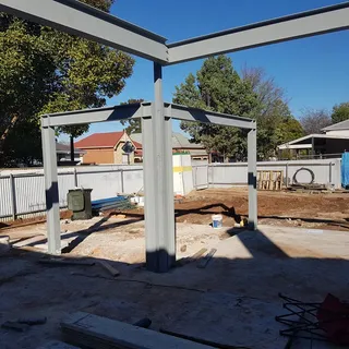 Grey structural steel beam frames across a residential site