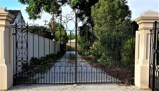 Ornate double wrought iron driveway gate with scrollwork
