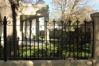 Wrought iron garden fence between rendered pillars