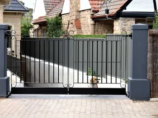 Black metal driveway gate with simple scroll details