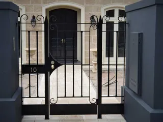 Pair of black wrought iron pedestrian gates at a front entry