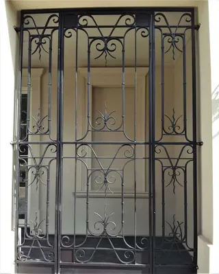 Tall wrought iron security gate with repeated decorative motifs