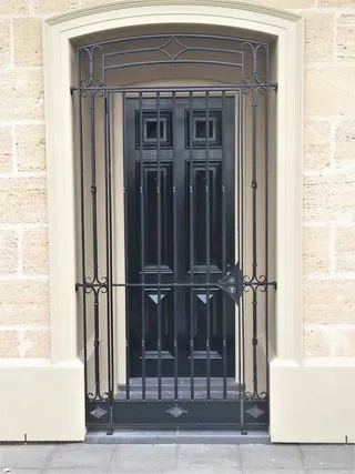 Wrought iron security gate fitted over a black front door