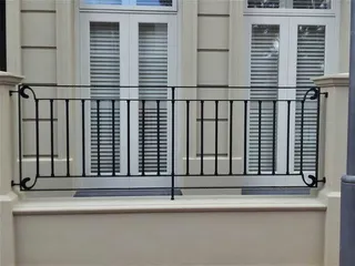 Simple wrought iron balustrade in front of tall windows