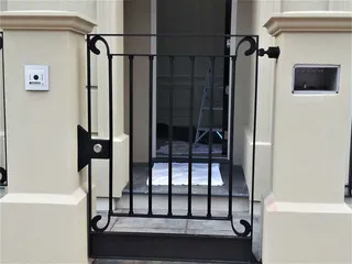 Small black metal pedestrian gate between entry pillars