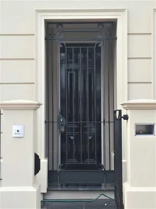 Tall wrought iron security gate installed at a front entry