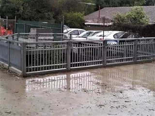 Grey metal safety fence and gate around an outdoor area