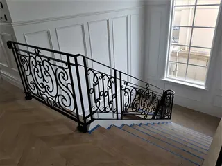 Decorative wrought iron balustrade descending an interior staircase
