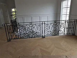 Wrought iron landing balustrade with repeated scroll patterns