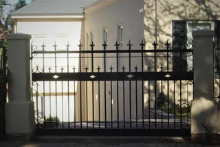 Black wrought iron driveway gate with spearhead finials